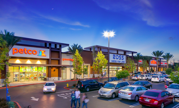 Strip mall storefronts at twilight with parking and signage